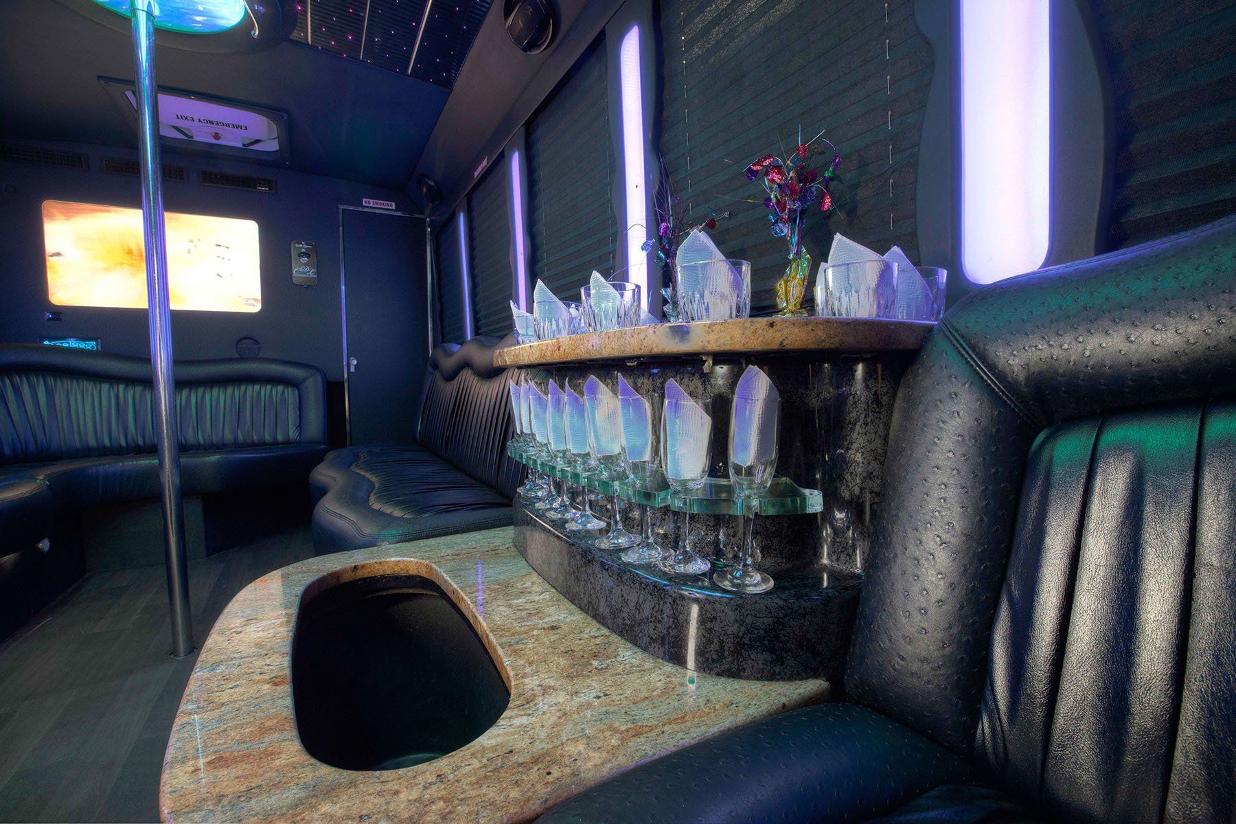 white E450 20 passenger party bus interior bar area with glasses and black seating