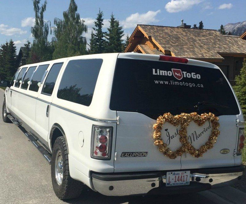 a white limousine with a wreath on the back that says just married