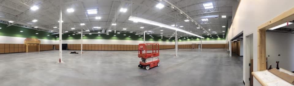A large empty warehouse with a forklift in the middle of it.