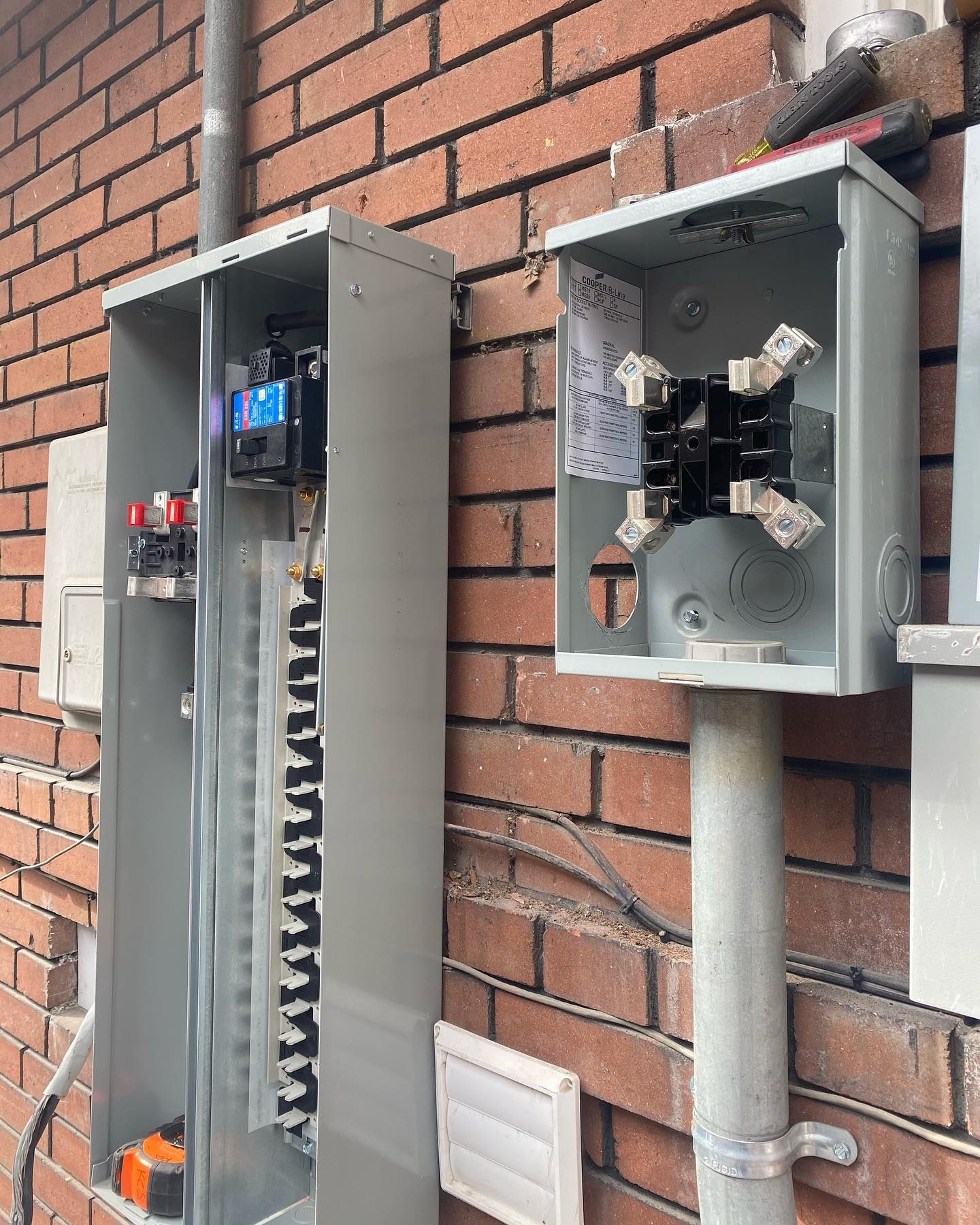 A brick wall with electrical boxes attached to it