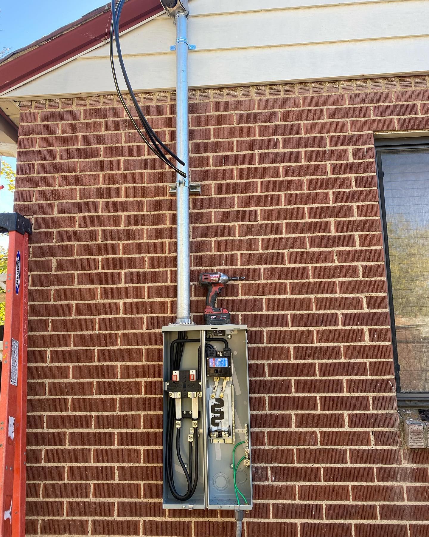 A brick wall with a box on it and a ladder next to it.