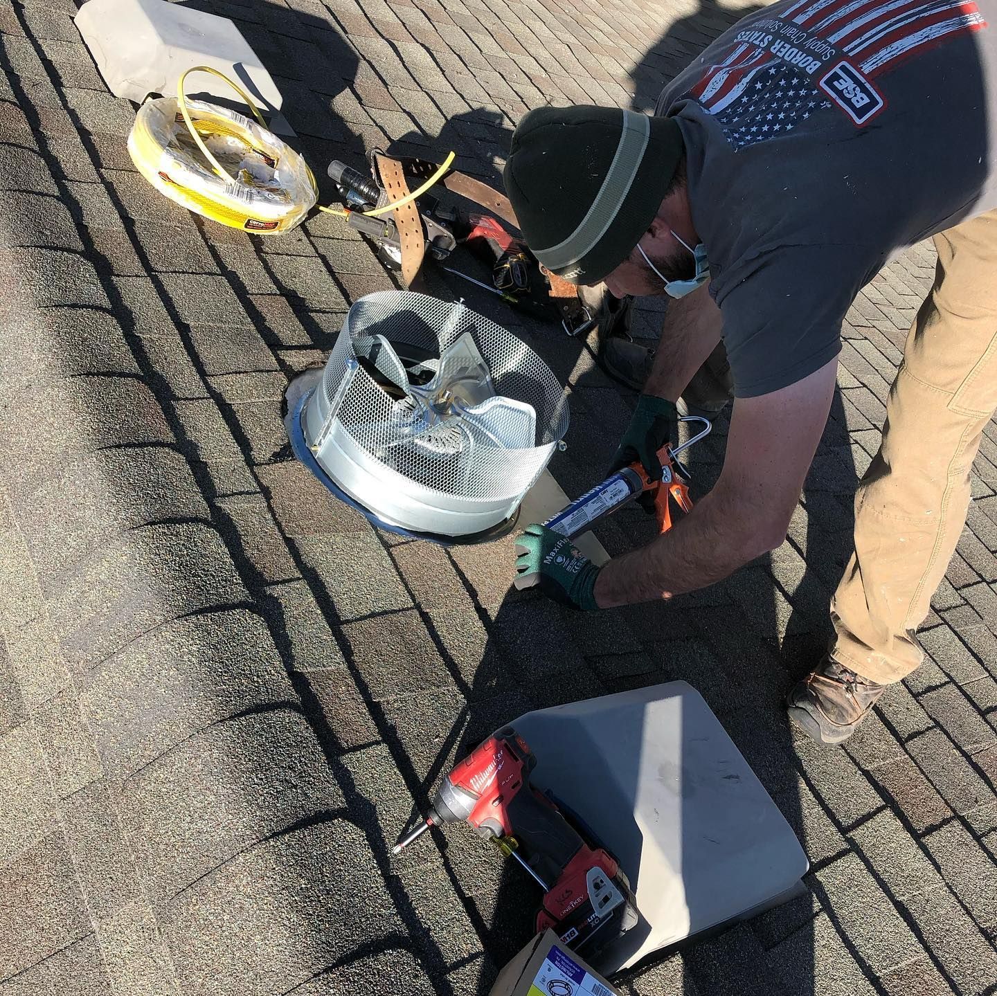 A man in an american flag shirt is working on a roof