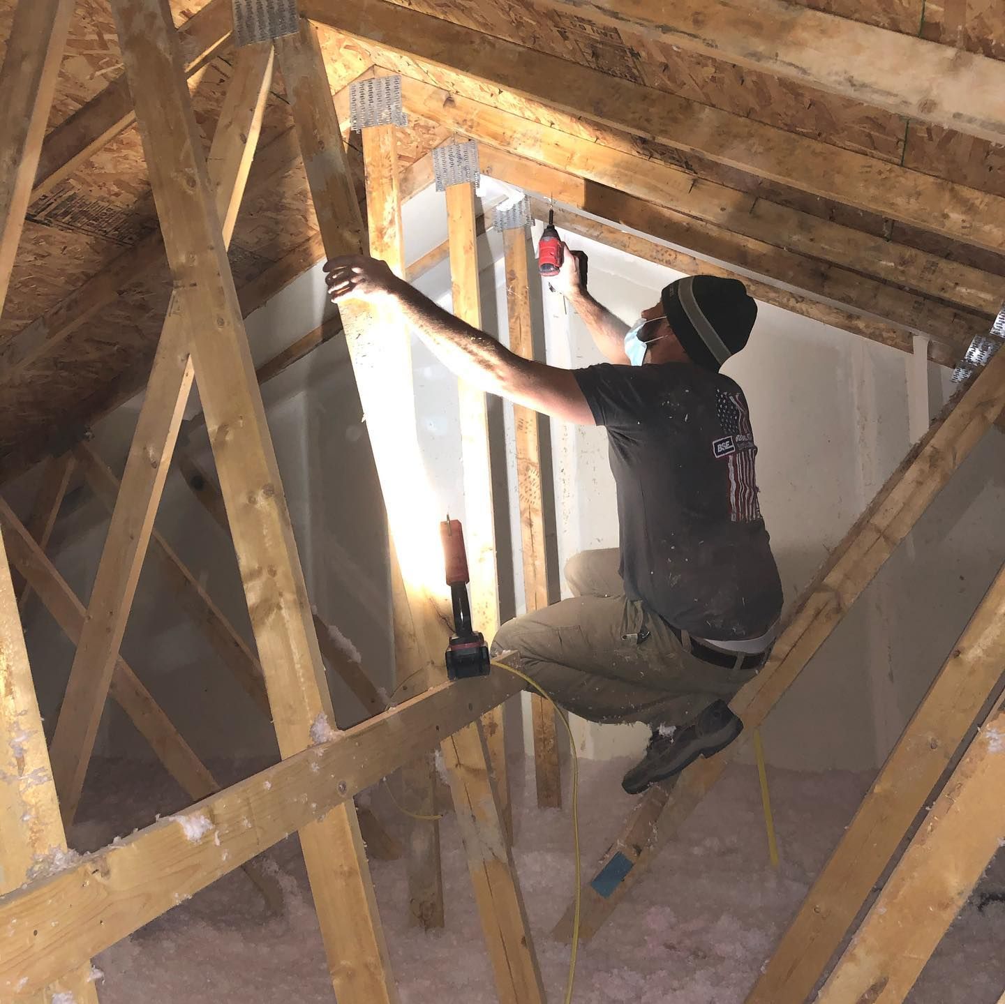 A man is sitting on a wooden ladder in an attic