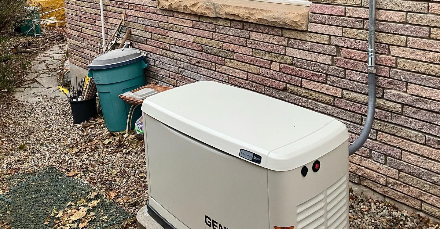 A generator is sitting on the side of a brick building.