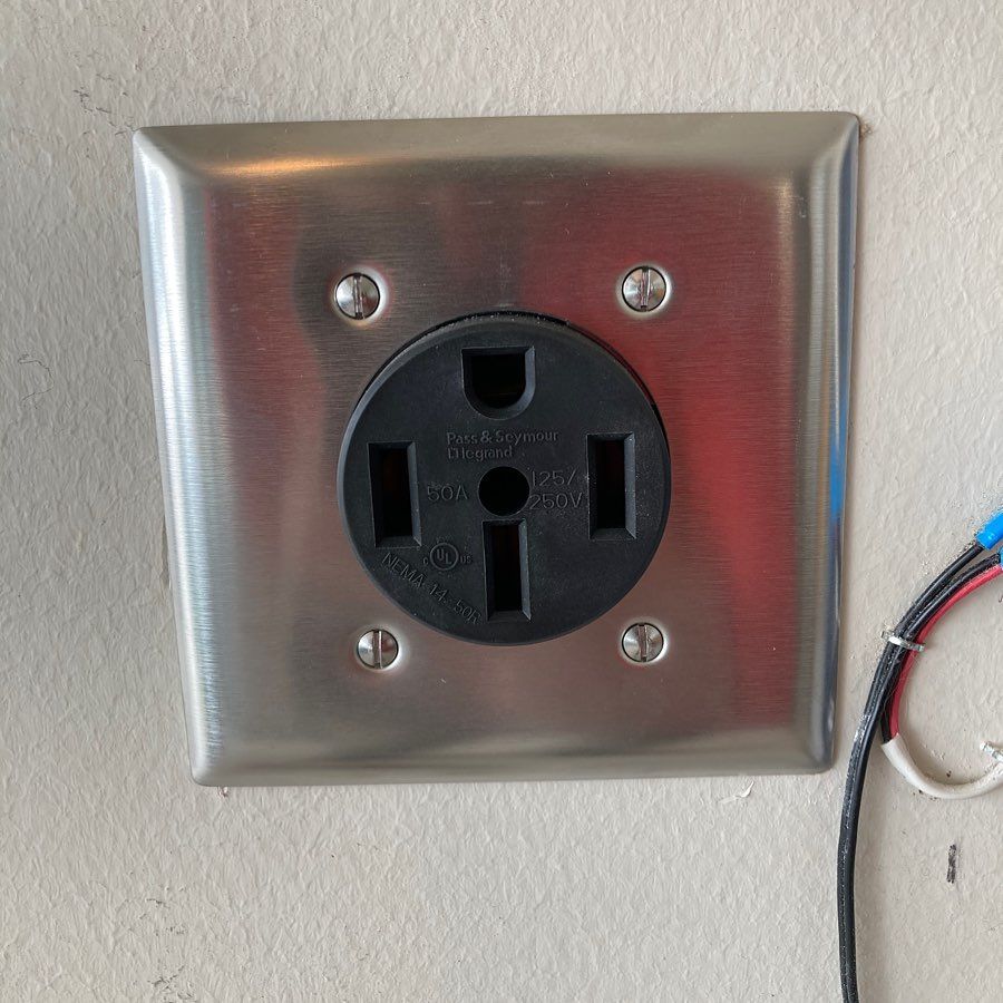 A stainless steel electrical outlet on a white wall