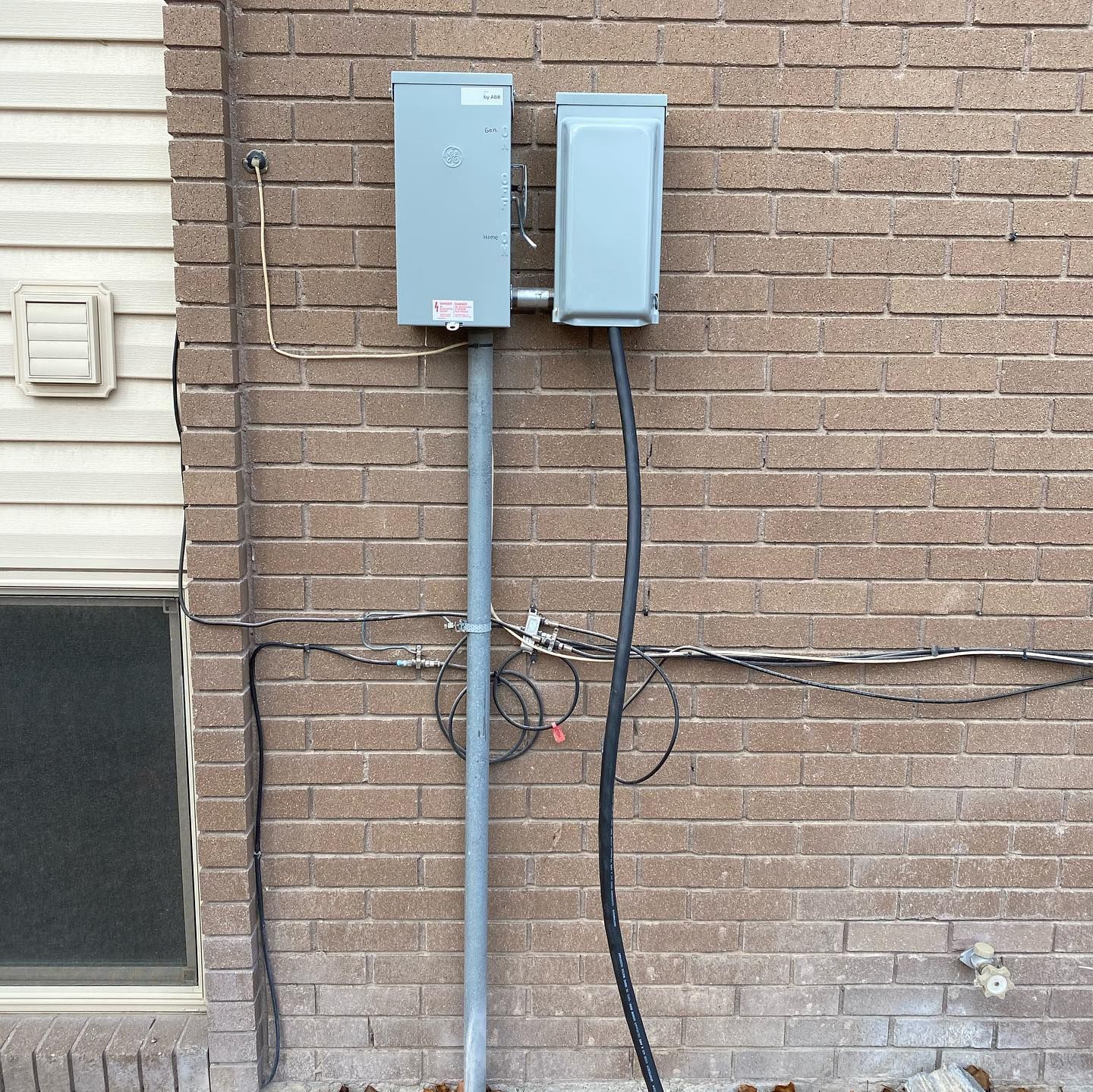 A brick wall with two electrical boxes attached to it