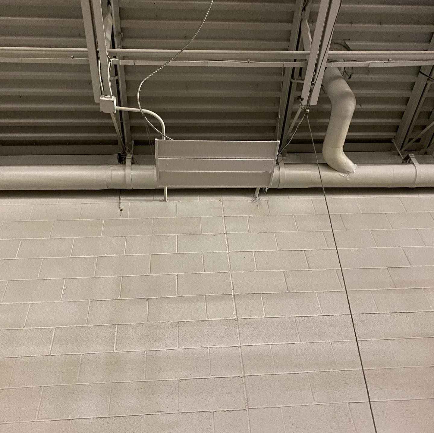 A white pipe is hanging from the ceiling of a building
