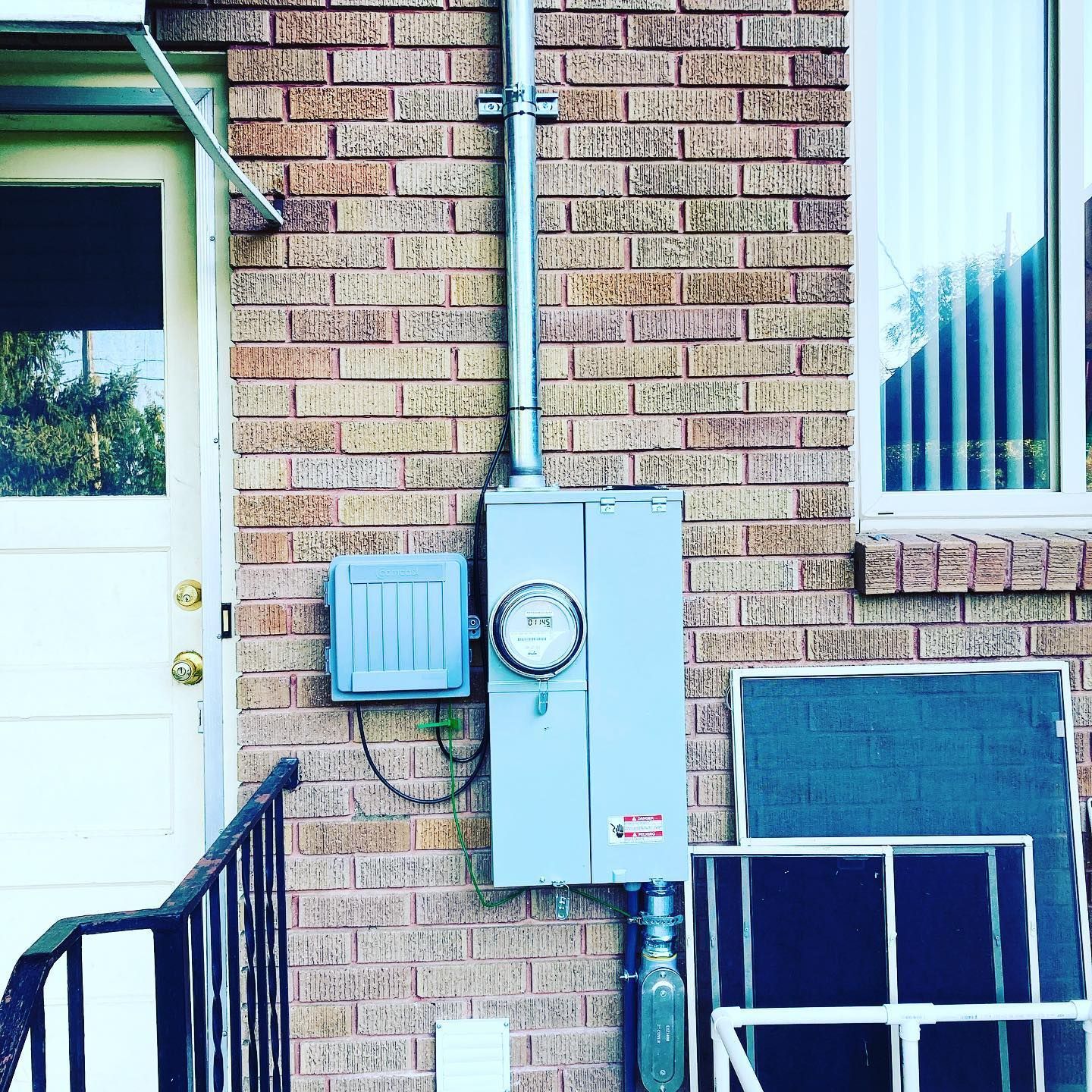 A brick wall with a meter on it and a door.