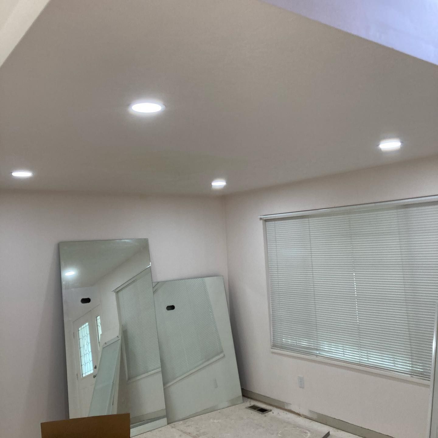 A room with two mirrors and a window with blinds.