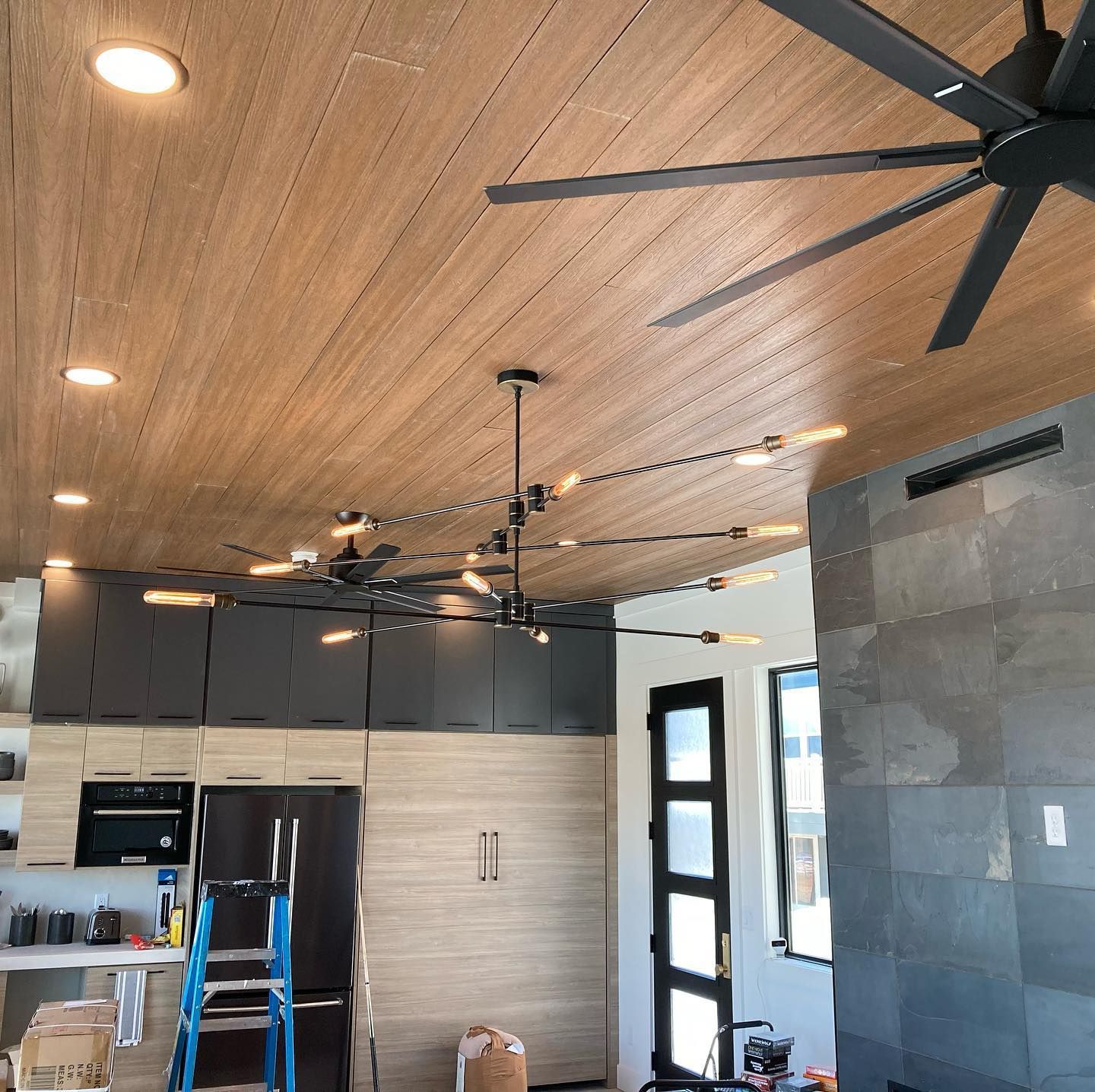 A kitchen with a wooden ceiling and a ceiling fan