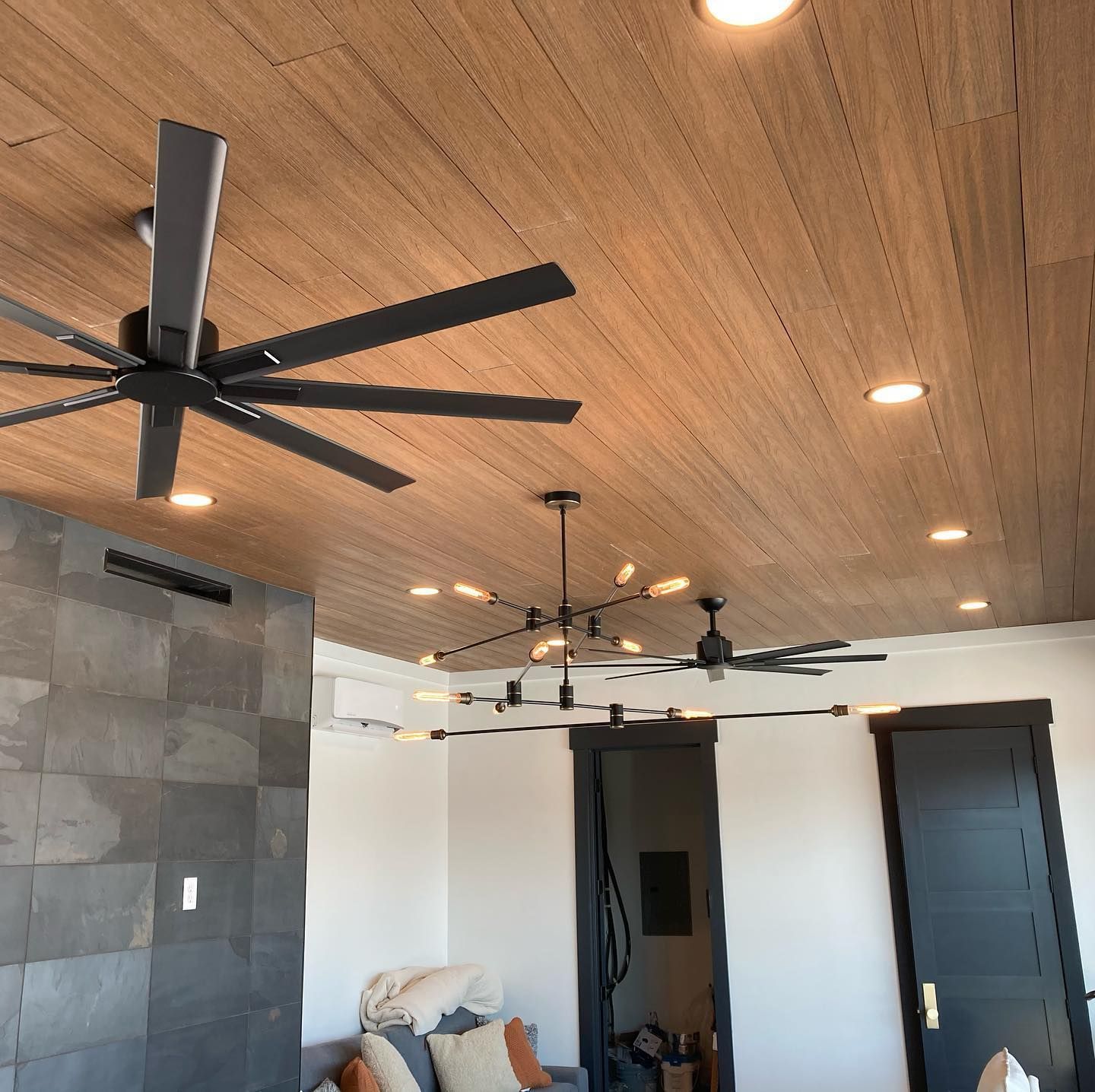 A living room with a wooden ceiling and ceiling fans