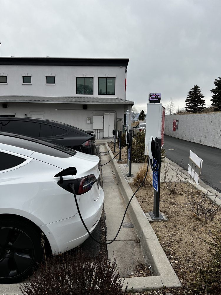 A white tesla model 3 is being charged at a charging station.