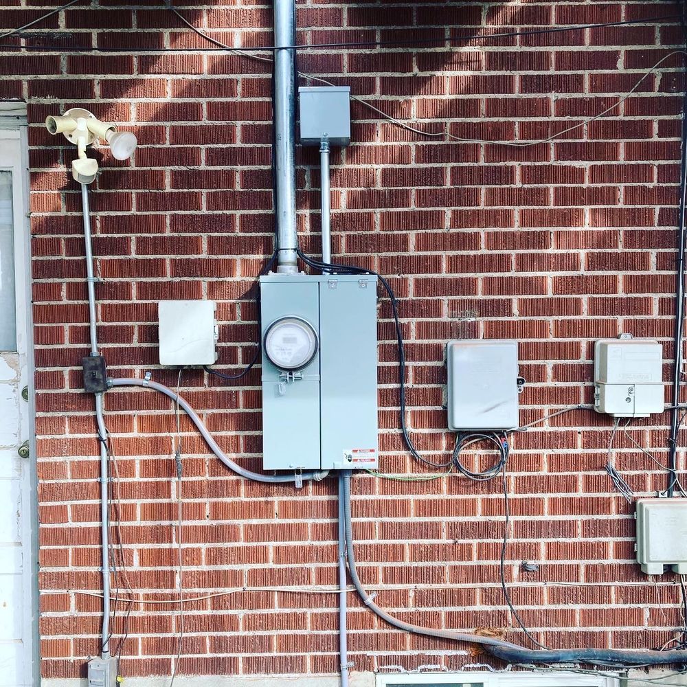 A man is working on an electrical box in a garage.
