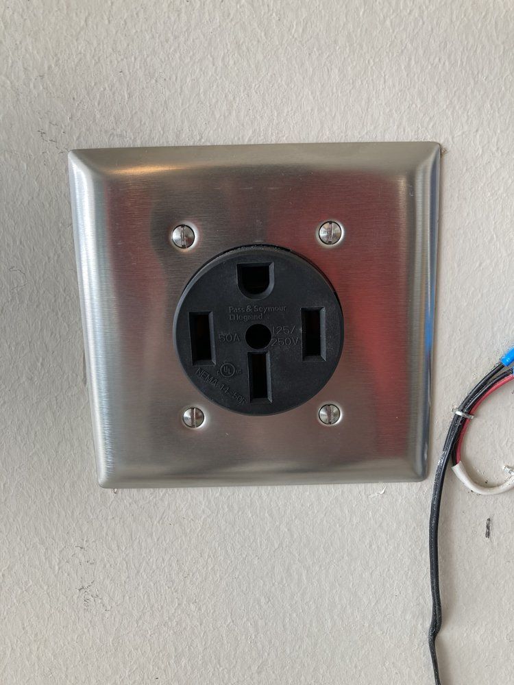 A close up of a stainless steel electrical outlet on a wall.