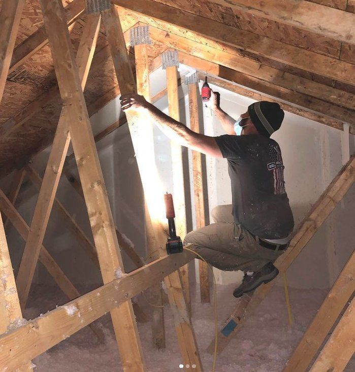 A man is sitting on a ladder working on a wooden structure