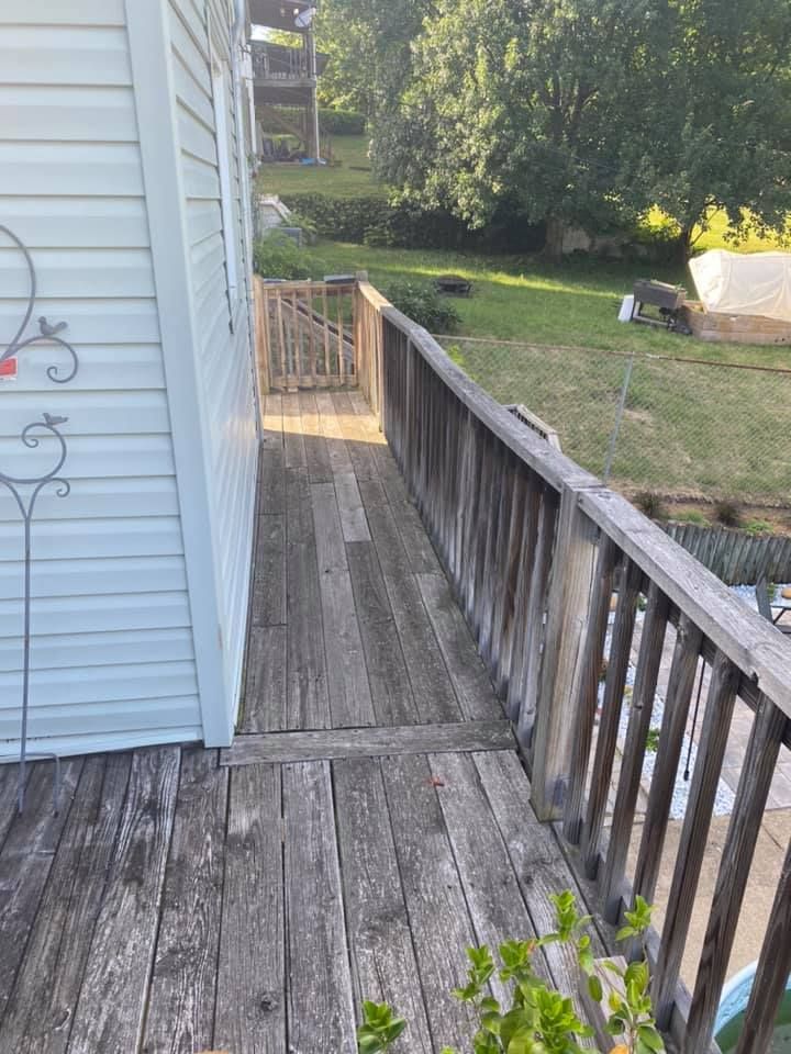 A before image of a weathered wooden deck runs alongside the side of a house with white siding