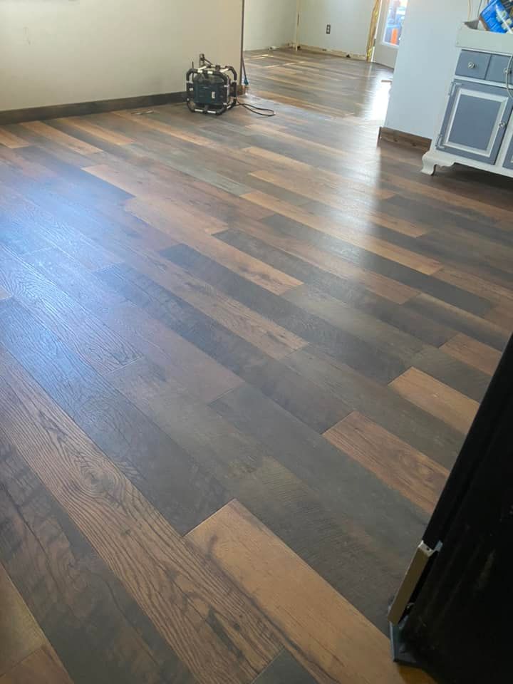 A bright, indoor room with brown and gray wood-look plank flooring, a small black equipment bag, and a white cabinet.