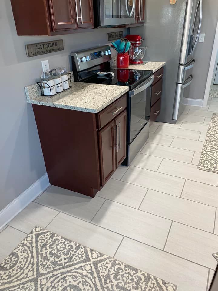 A kitchen featuring a stainless steel stove, granite countertops, dark brown cabinetry, and light-colored tiled flooring.