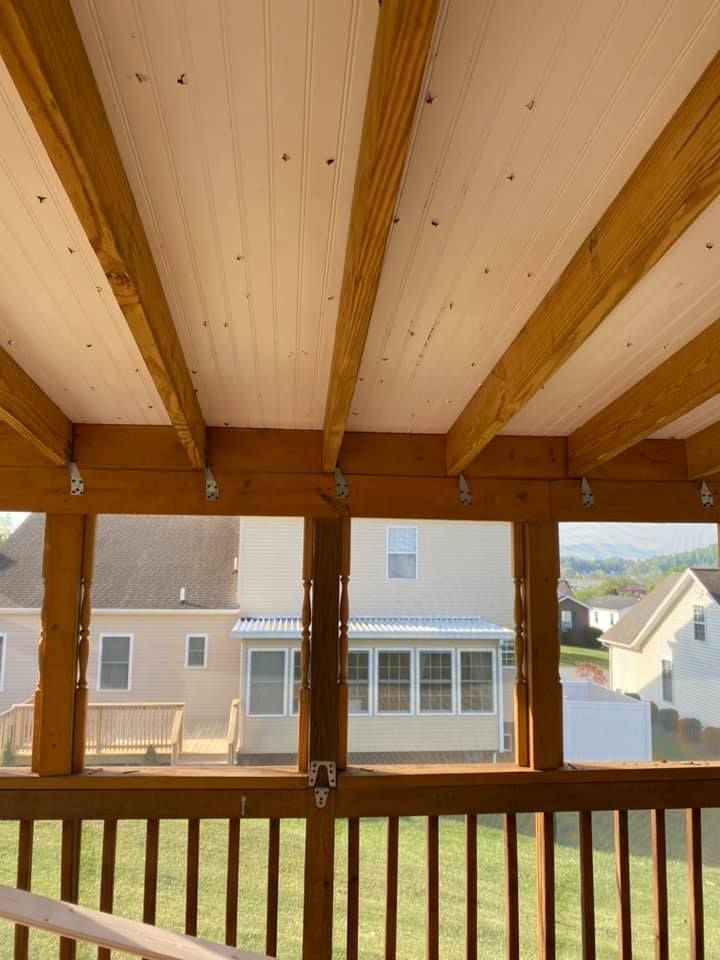 View from a wooden covered porch looking out over a grassy yard toward neighboring houses.
