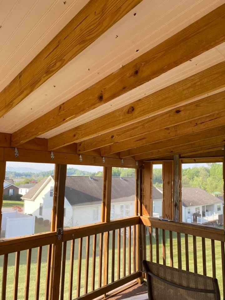 A view from a wooden covered porch looking out toward suburban houses and a green lawn on a sunny day.