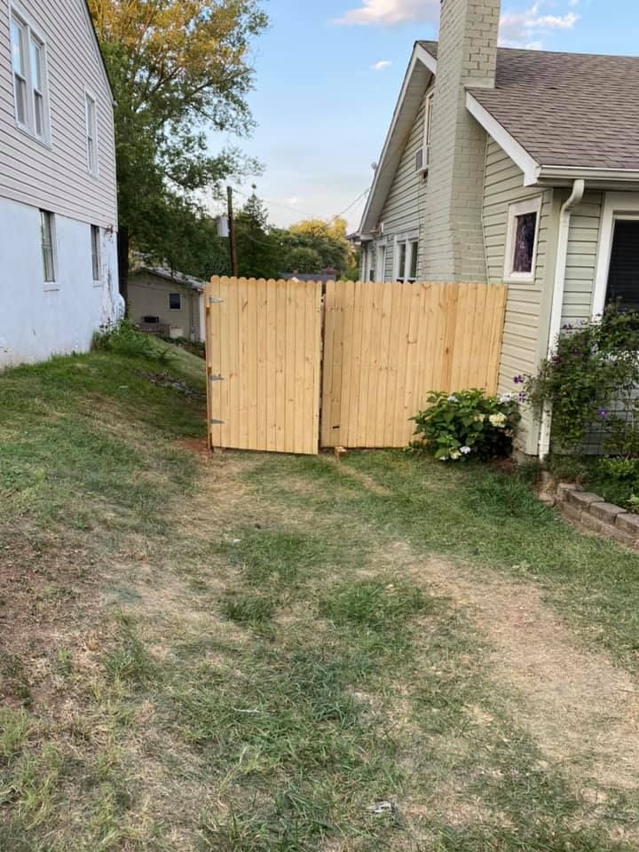 A new wooden fence stands between two houses on a grassy yard, creating a barrier between the properties.
