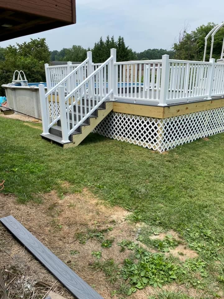 An elevated deck with white railings and stairs leading to an above-ground swimming pool in a grassy backyard.