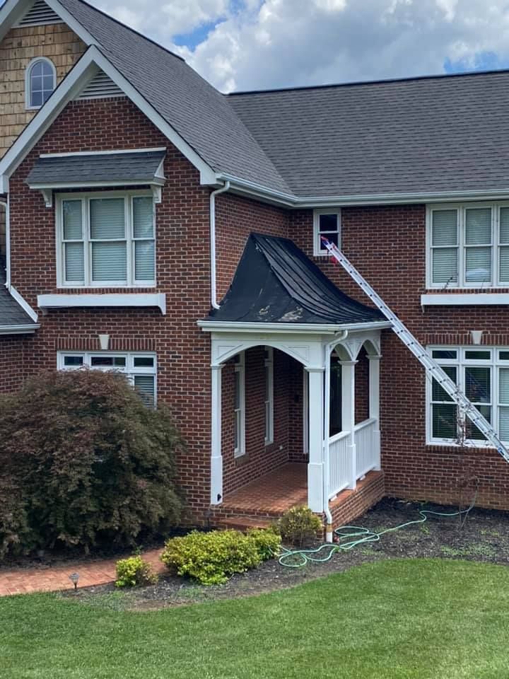 A before image of a two-story red brick house features a white front porch with a dark metal roof and a ladder resting