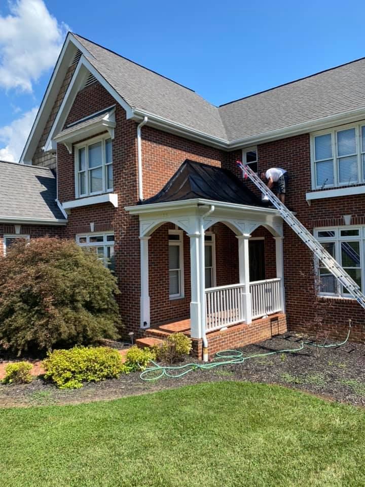 An after image of an R & D Construction worker on a ladder finishing the paint job on an overhang.