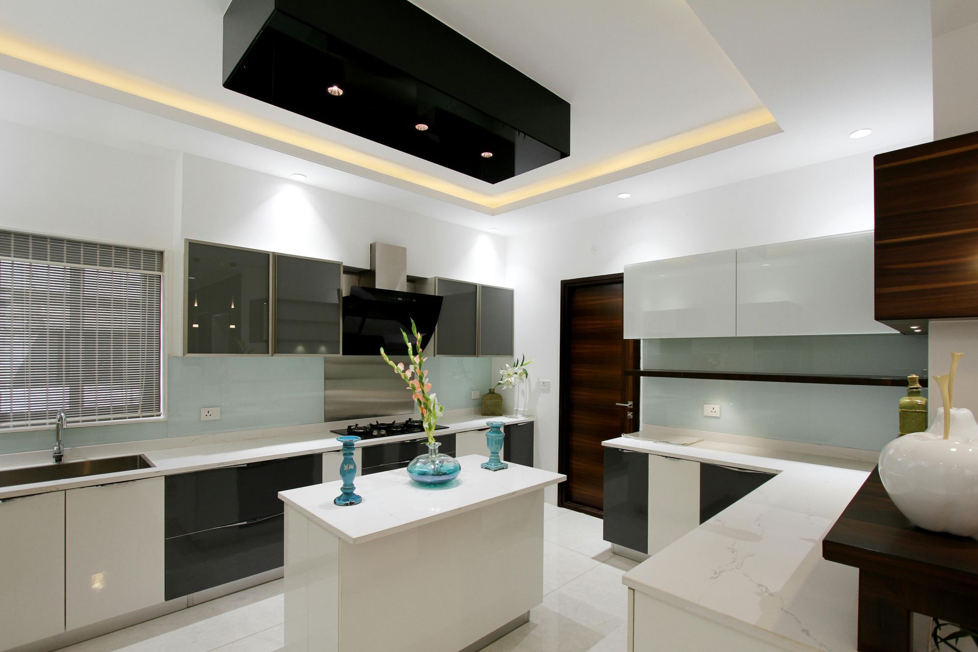 A modern kitchen with white and dark gray cabinets, a central island, light countertops, and a black ceiling fixture.
