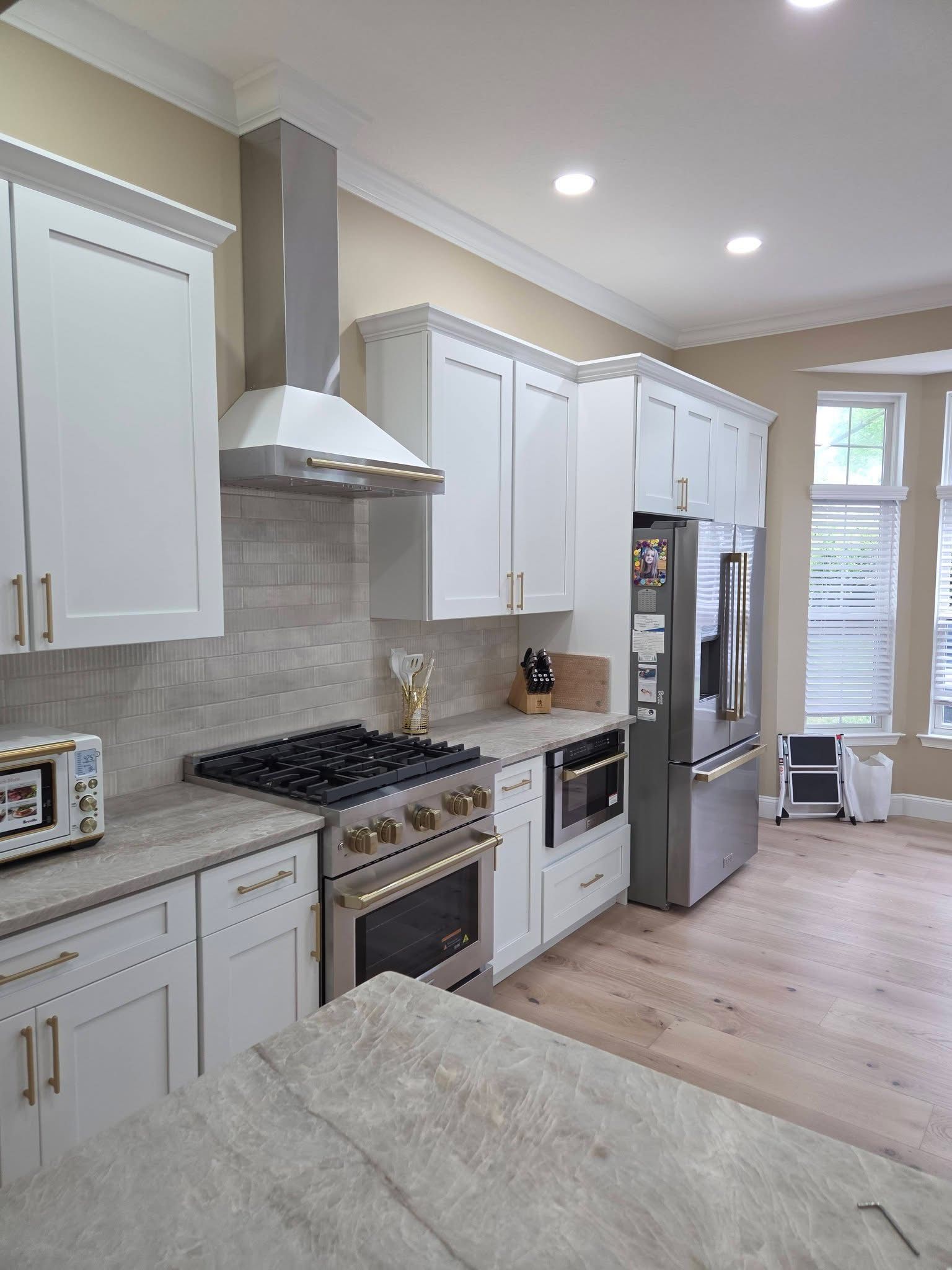 Modern kitchen with white cabinets, stainless appliances, and a large island with light stone countertop