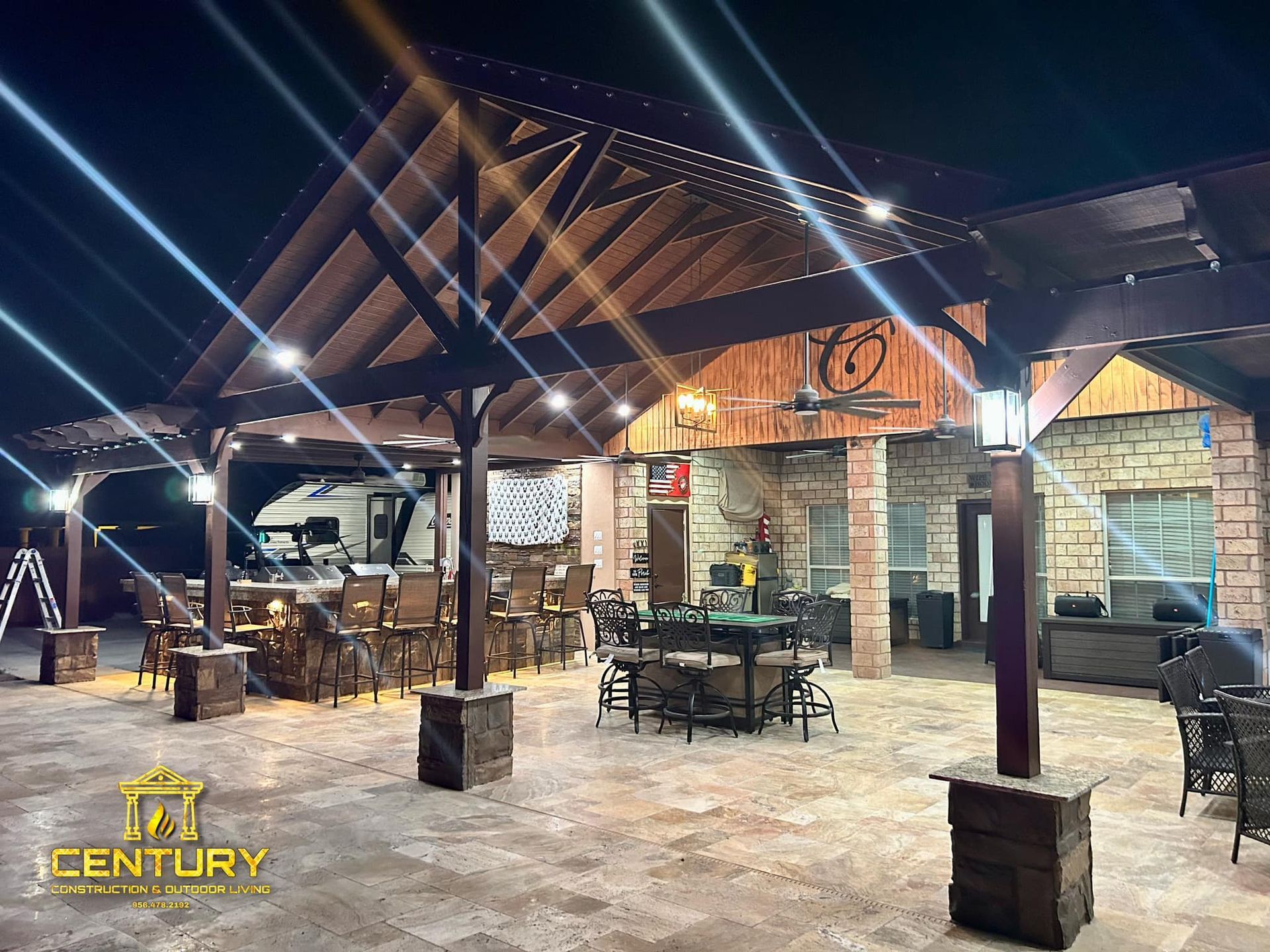 A large patio area with tables and chairs under a wooden roof.