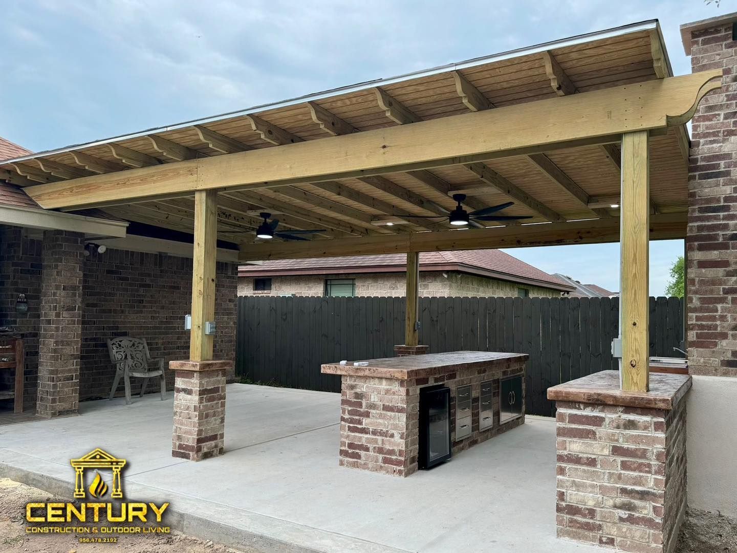 A patio with a wooden pergola and a brick table.
