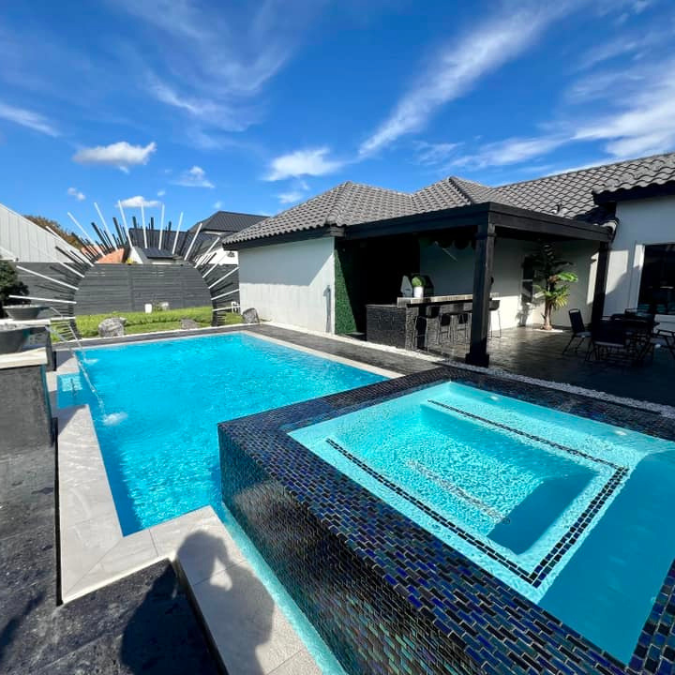 A large swimming pool with a hot tub next to it