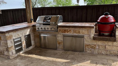 An outdoor kitchen with a grill and a red pot.