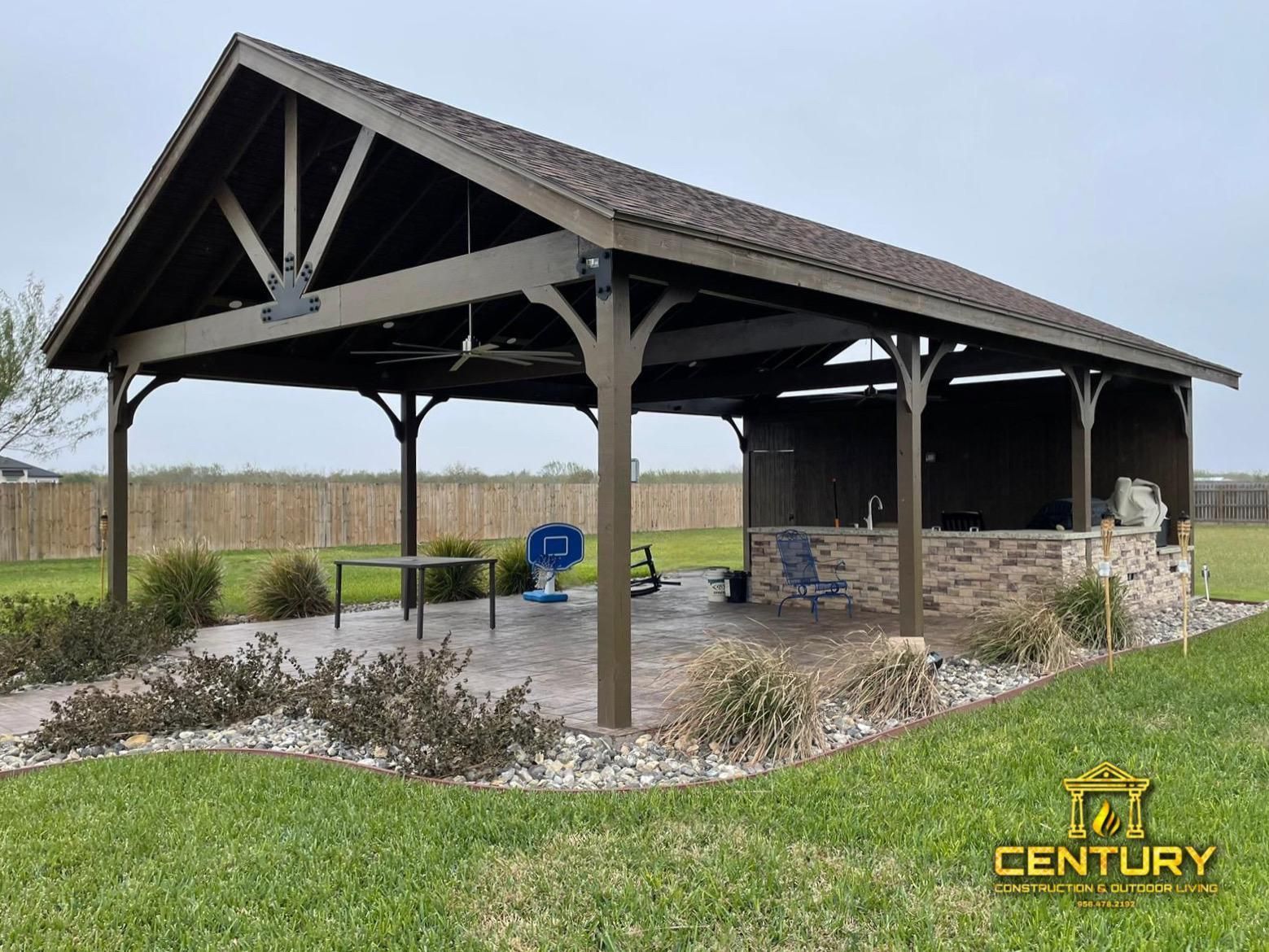 A large wooden pavilion is sitting in the middle of a lush green field.