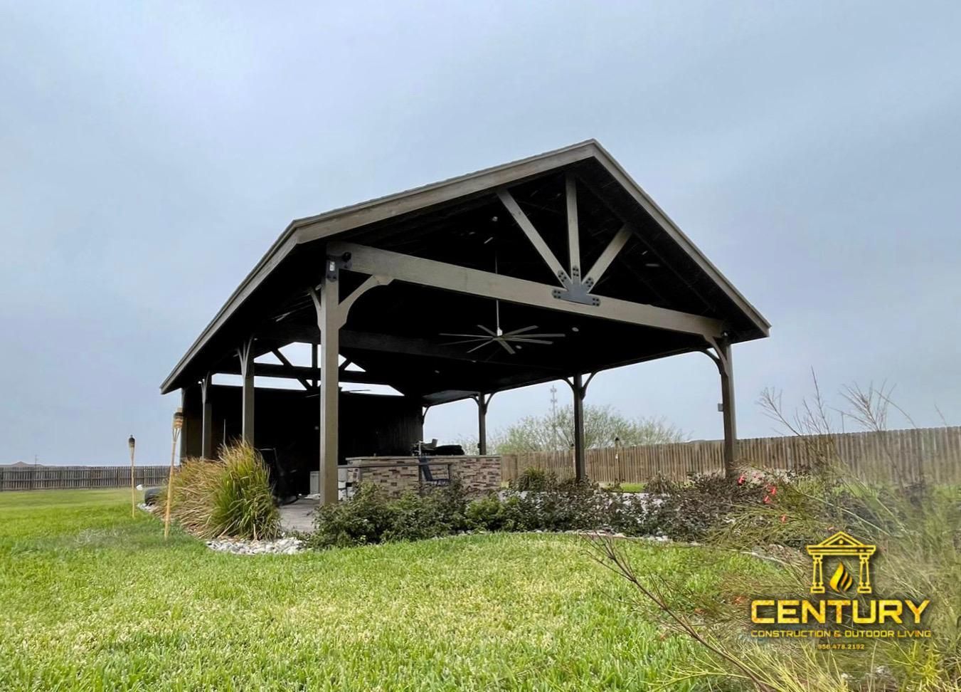 A large wooden pavilion is sitting in the middle of a grassy field.