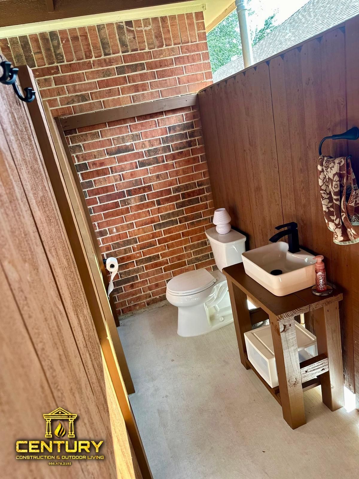 A bathroom with a toilet , sink , and brick wall.