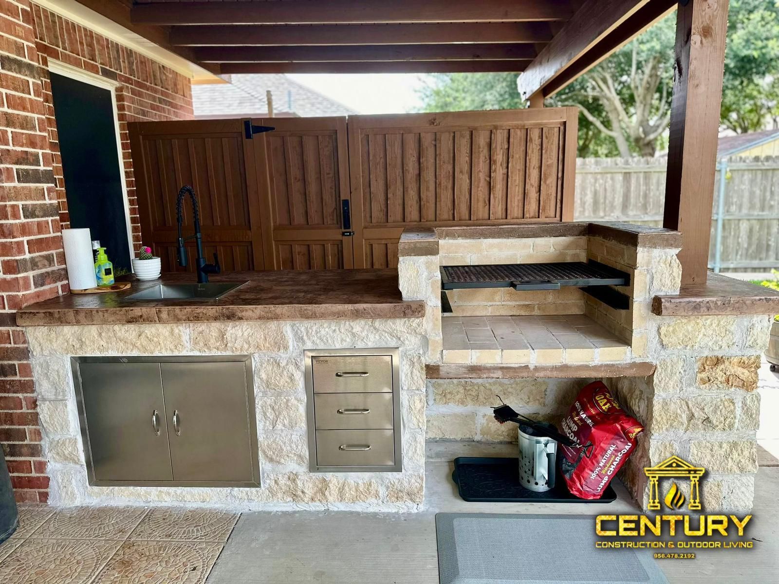 A kitchen with a sink and a grill under a covered patio.