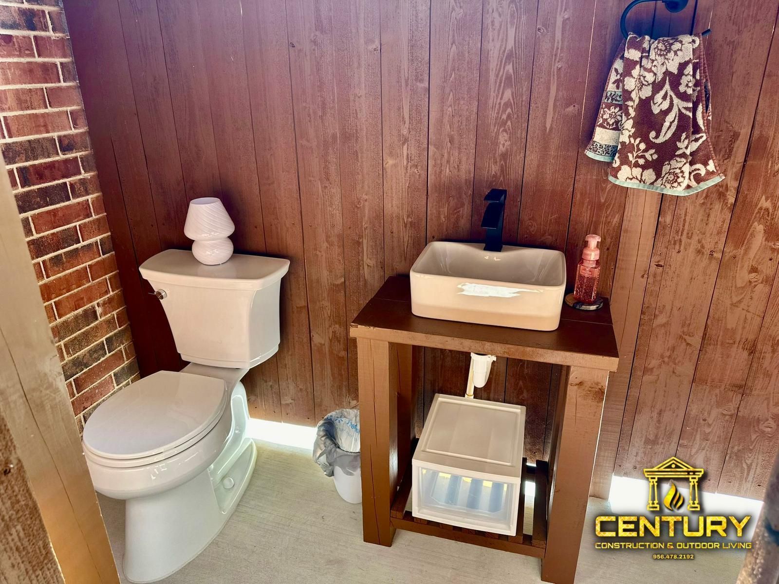 A bathroom with a toilet , sink and wooden wall.