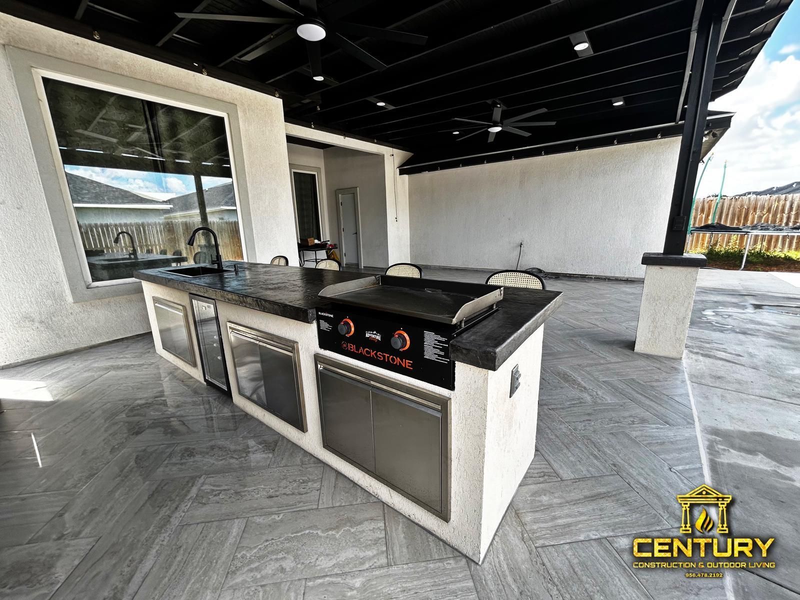 A large outdoor kitchen with a grill and a sink.