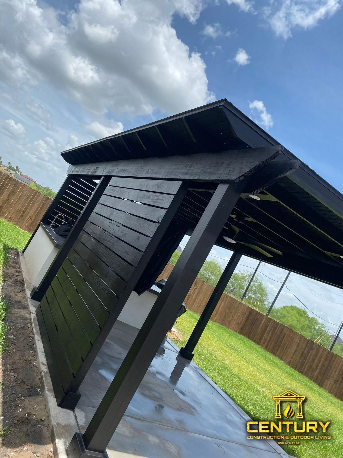 A black pergola is sitting in the middle of a backyard.