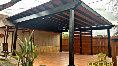 A carport with a roof and a fence in front of a house.