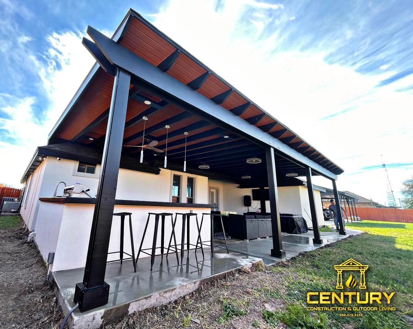 A white house with a pergola and a kitchen in the backyard.