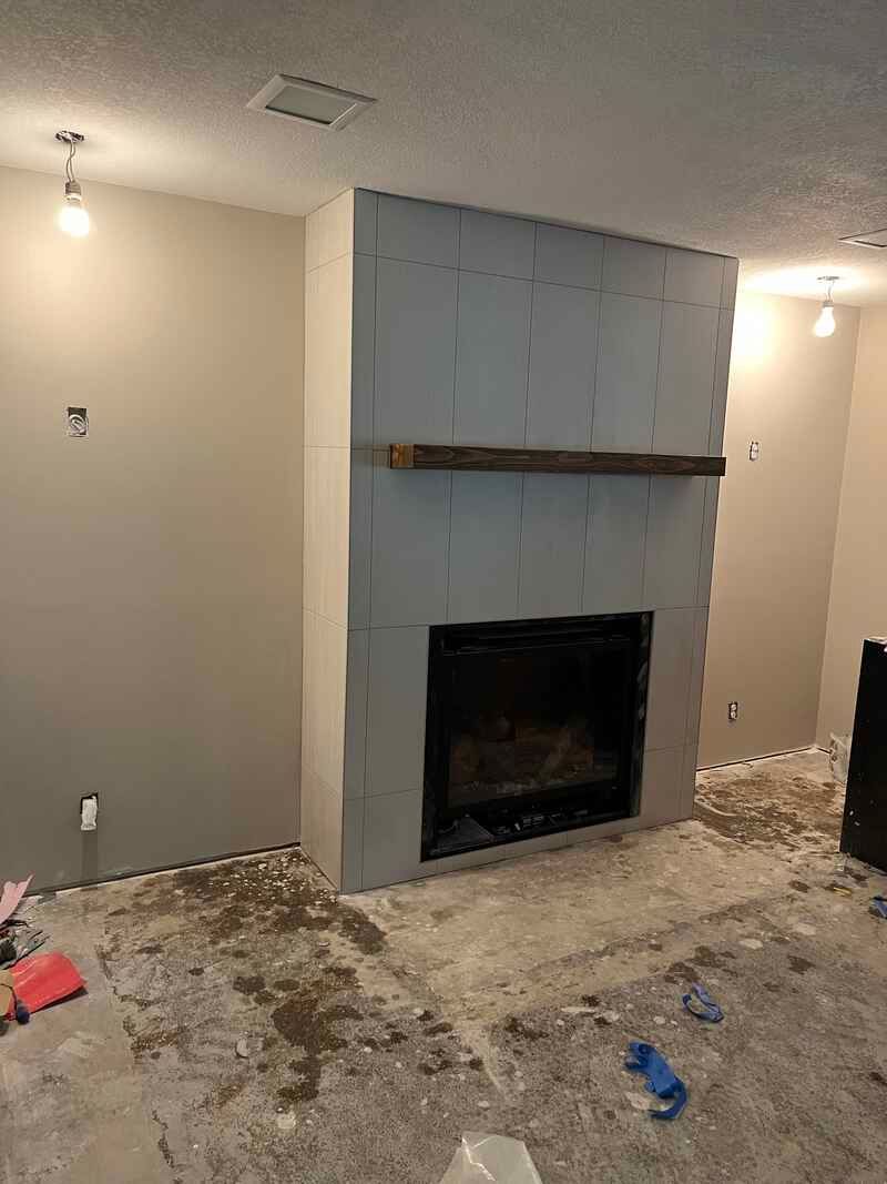 A living room with a fireplace and a shelf on the wall.
