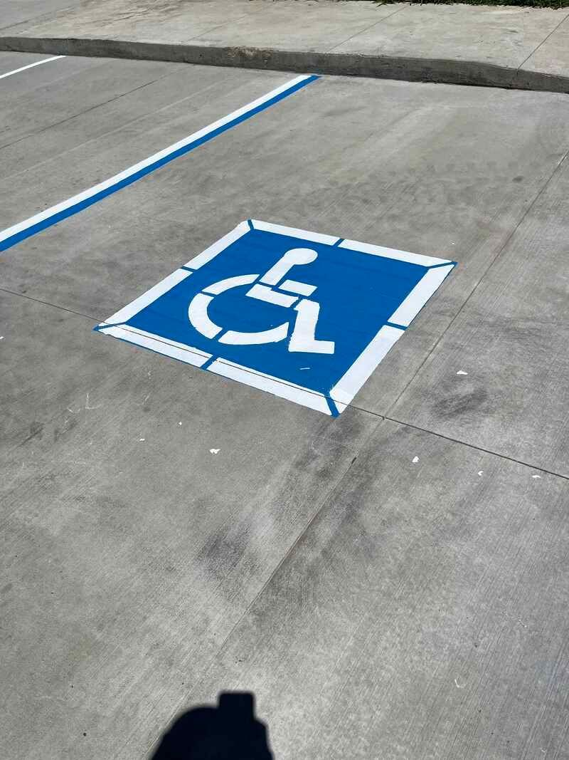 A handicap sign is painted on the ground in a parking lot.