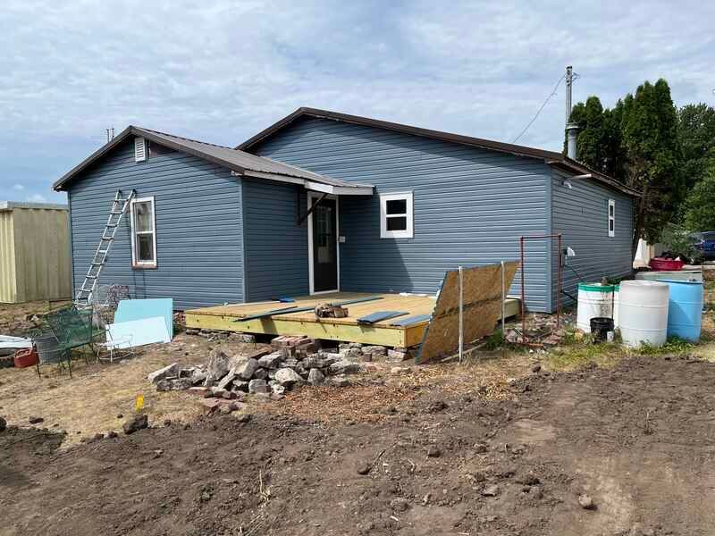 A blue house is being built in a dirt field.
