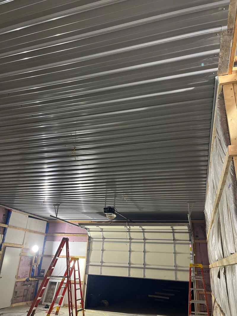 A garage under construction with a ladder and a garage door.