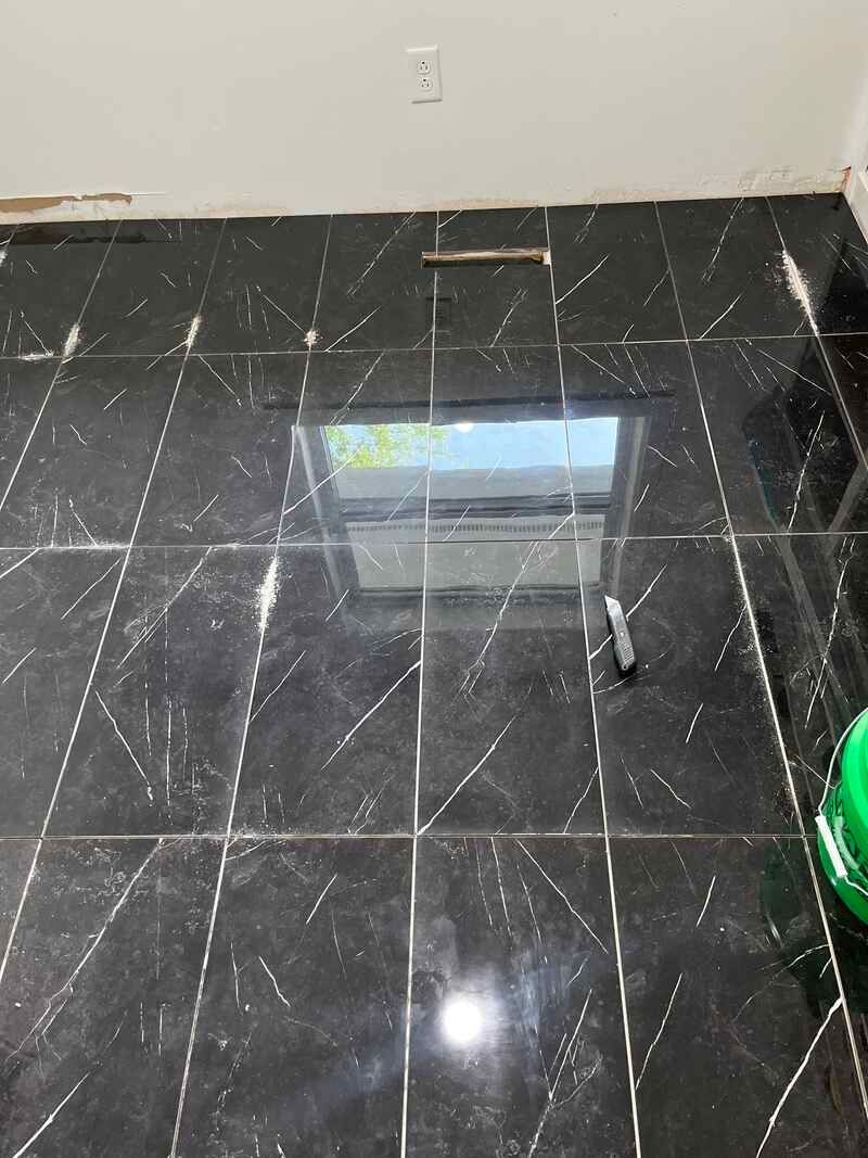 A black tiled floor with a glass table in a room.