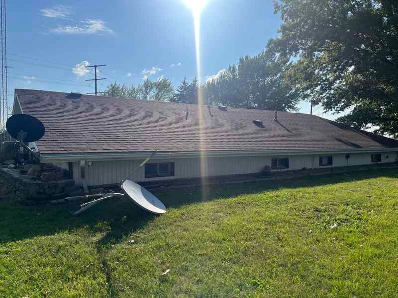 The back of a house with a satellite dish on the roof.