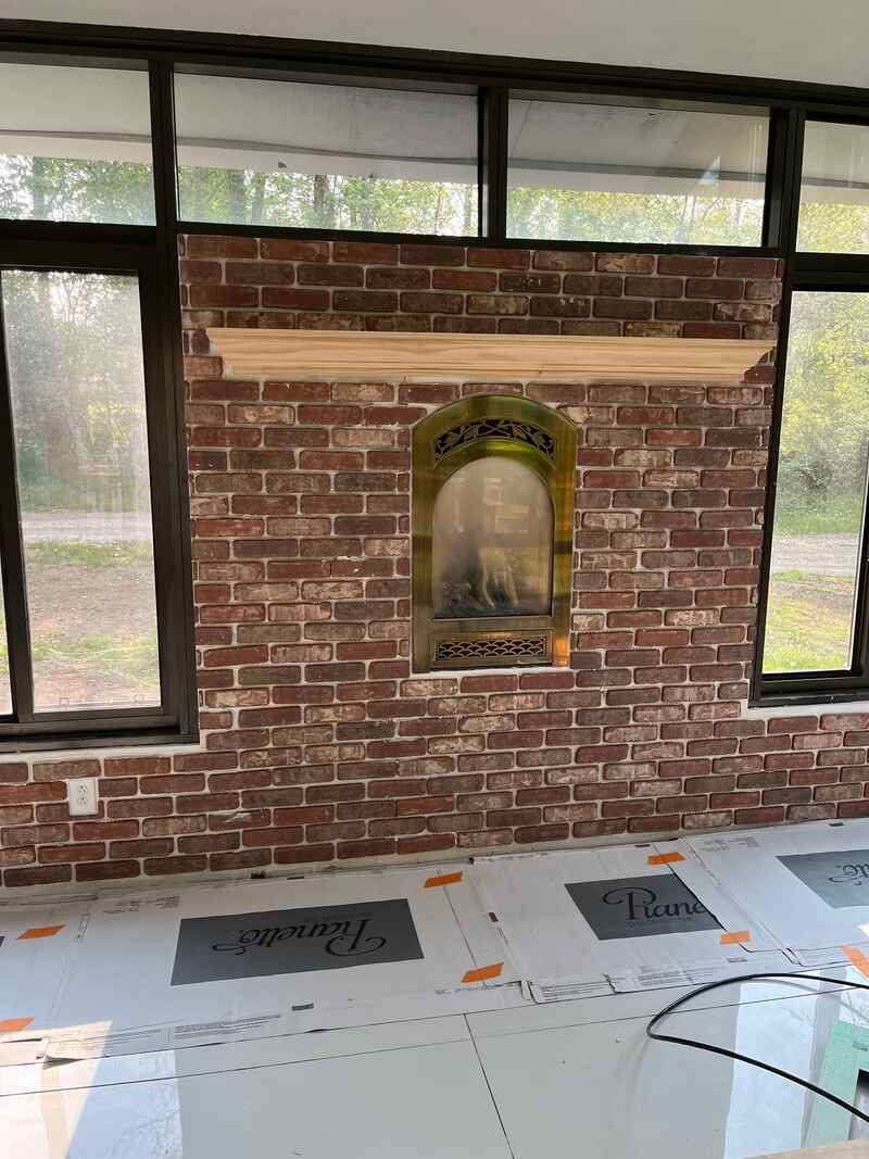 A living room with a fireplace and a brick wall.